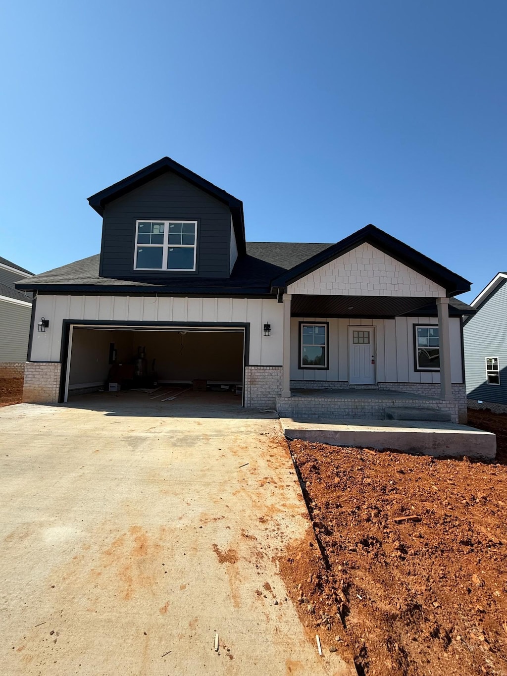 modern farmhouse featuring driveway, board and batten siding, and brick siding