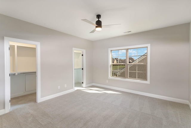 unfurnished bedroom featuring carpet floors, visible vents, a spacious closet, and baseboards