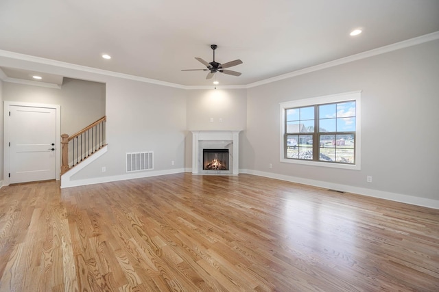 unfurnished living room with crown molding, light wood-style floors, visible vents, and baseboards