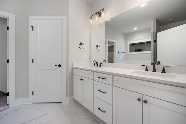 bathroom featuring marble finish floor, a sink, baseboards, and double vanity