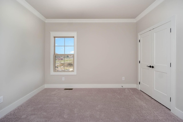 unfurnished bedroom featuring a closet, visible vents, ornamental molding, carpet flooring, and baseboards