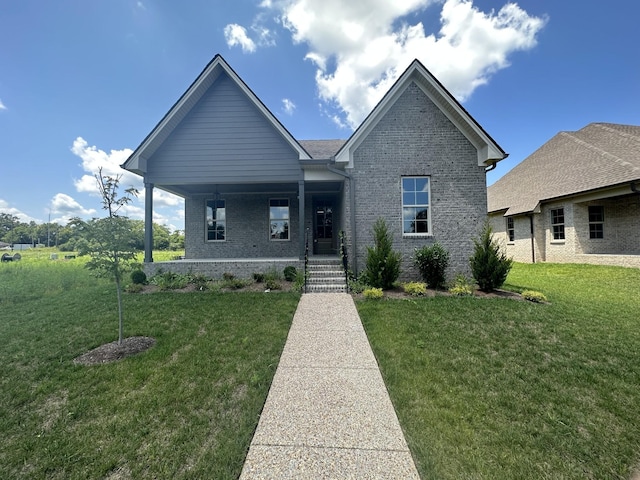 view of front facade featuring covered porch, brick siding, and a front lawn