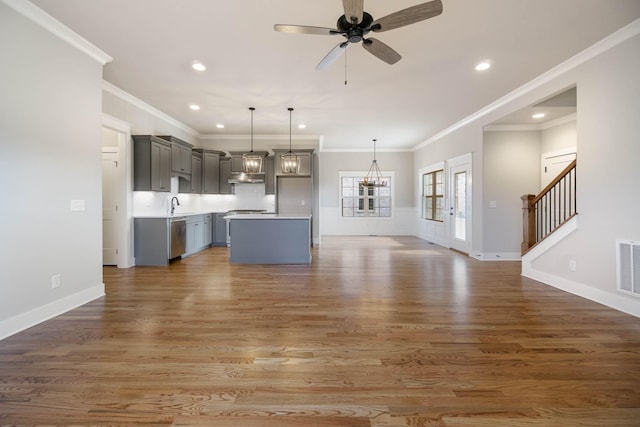 unfurnished living room featuring stairway, wood finished floors, ceiling fan with notable chandelier, a sink, and recessed lighting