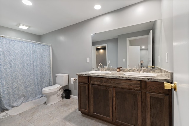 bathroom featuring toilet, double vanity, a sink, and tile patterned floors