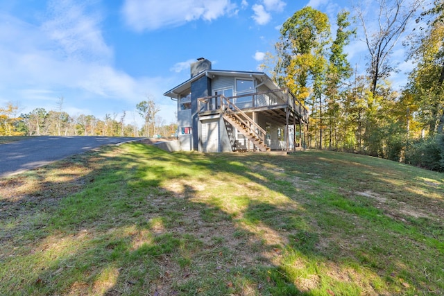 rear view of property with a chimney, stairway, a deck, and a lawn