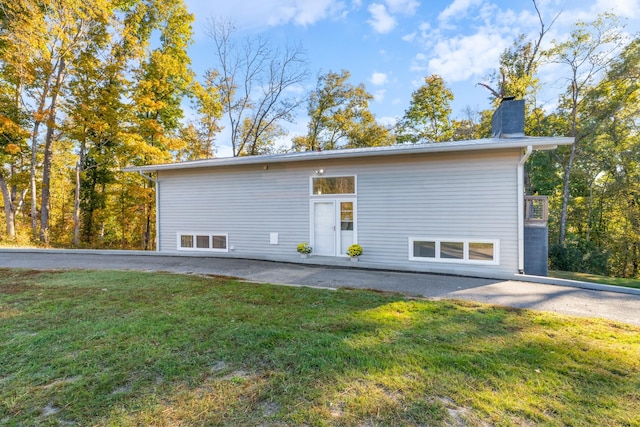 back of property featuring a chimney and a lawn