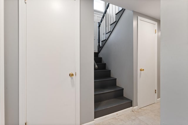 stairway with baseboards and tile patterned floors