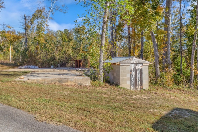 view of yard with an outbuilding, a storage unit, and a view of trees