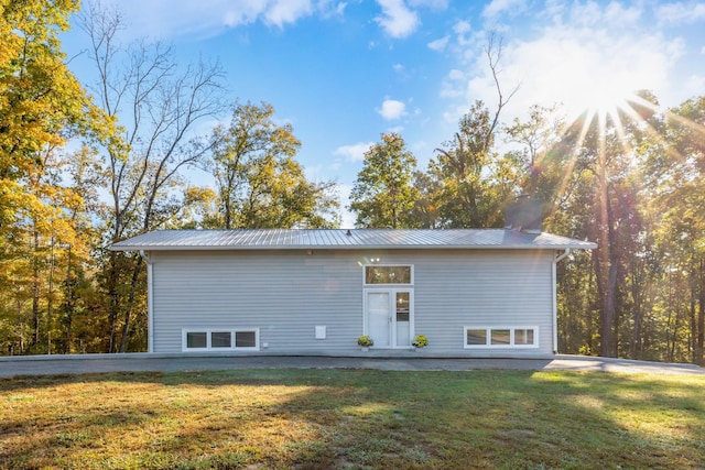 rear view of house featuring metal roof and a lawn