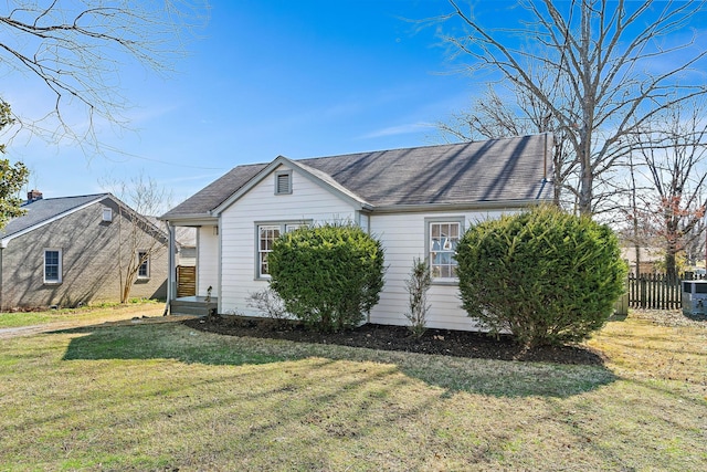 view of side of home featuring fence and a lawn