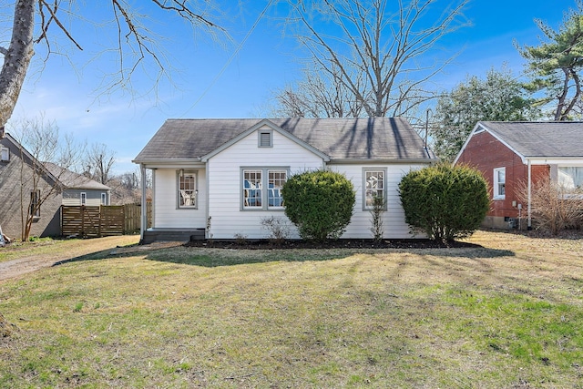 view of front of property with a shingled roof, a front yard, and fence