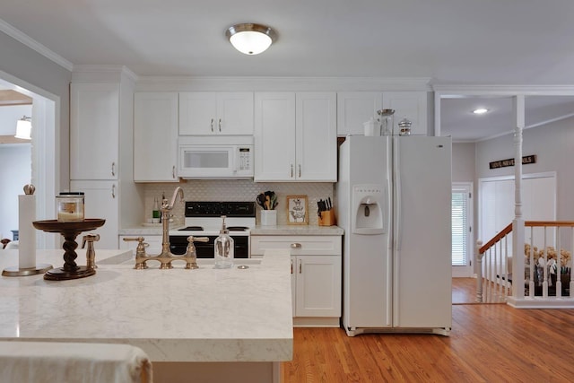 kitchen with white cabinets, white appliances, light wood-style floors, and a sink