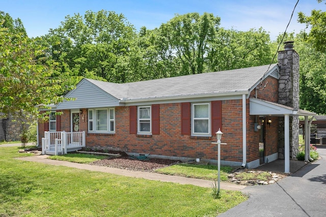 ranch-style house with aphalt driveway, brick siding, a chimney, a front yard, and an attached carport