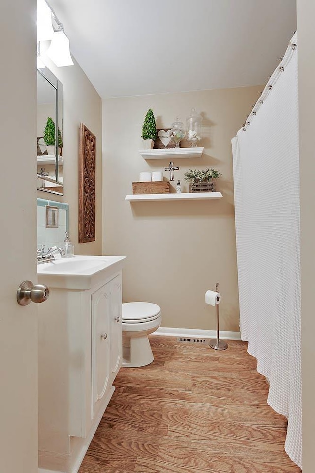 full bathroom featuring baseboards, vanity, toilet, and wood finished floors