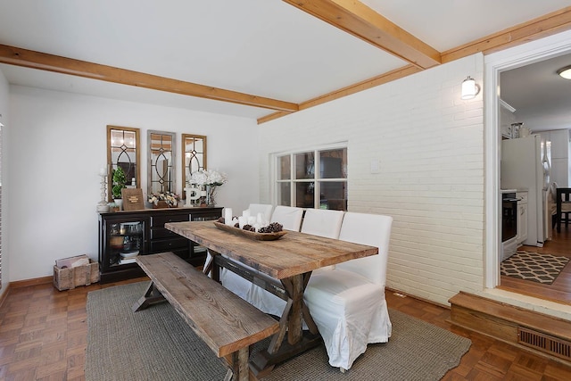 dining space with brick wall, wine cooler, beamed ceiling, and visible vents