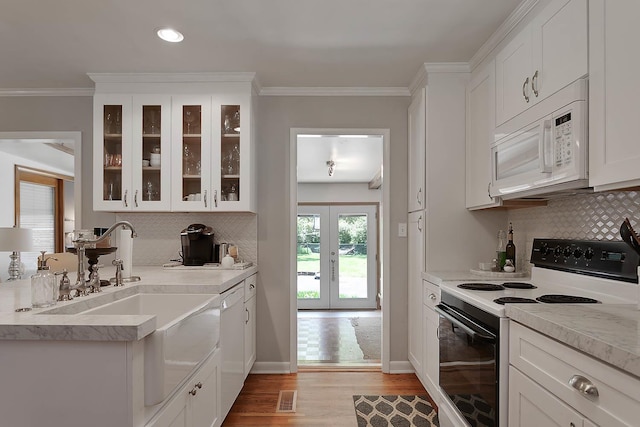 kitchen with light wood finished floors, electric range, white microwave, glass insert cabinets, and crown molding