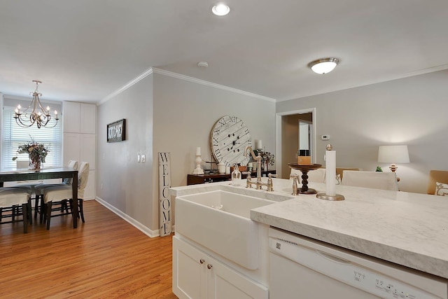 kitchen with dishwasher, light countertops, crown molding, light wood-style floors, and a sink