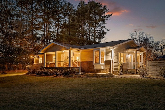 view of front facade with crawl space, brick siding, a yard, and fence