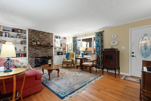 living area with ornamental molding, a fireplace, baseboards, and wood finished floors