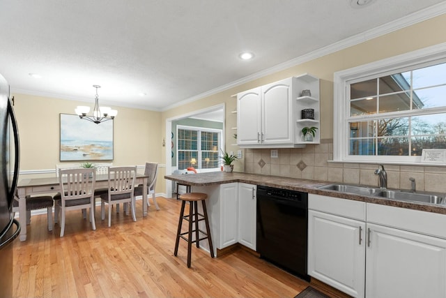 kitchen with a sink, white cabinets, a wealth of natural light, black appliances, and dark countertops