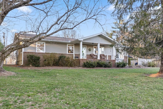 view of front of house featuring covered porch, a front lawn, and brick siding