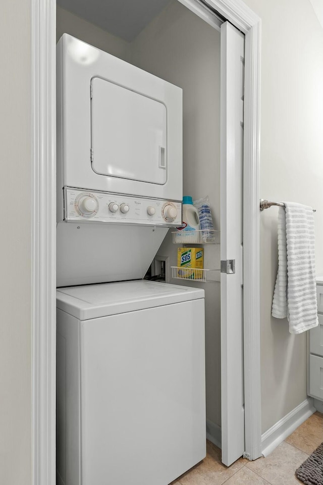 washroom with stacked washing maching and dryer, laundry area, baseboards, and light tile patterned flooring