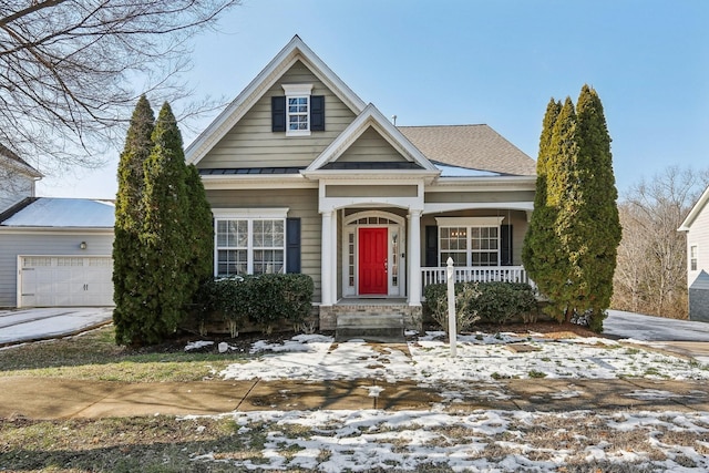 view of front of property with driveway, a garage, metal roof, a standing seam roof, and covered porch