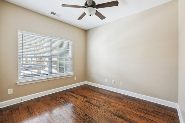 empty room featuring baseboards, visible vents, and dark wood-style flooring