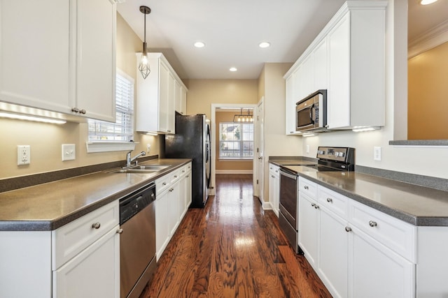 kitchen with plenty of natural light, appliances with stainless steel finishes, dark countertops, and a sink