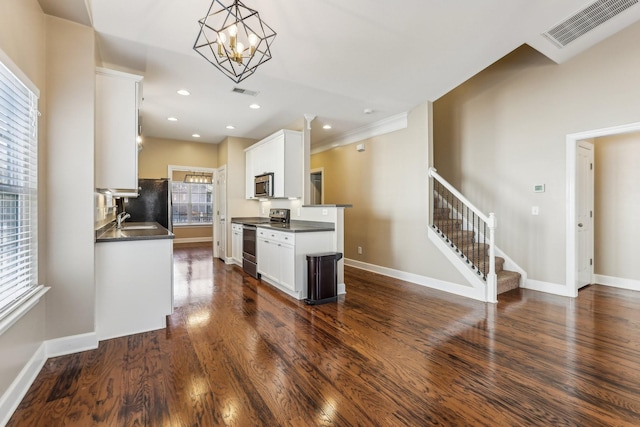 kitchen featuring dark countertops, visible vents, appliances with stainless steel finishes, and dark wood finished floors