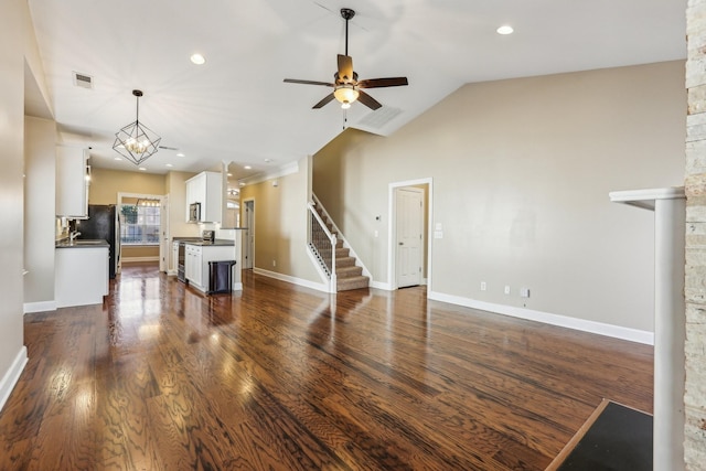 living room featuring stairs, dark wood-type flooring, vaulted ceiling, and visible vents