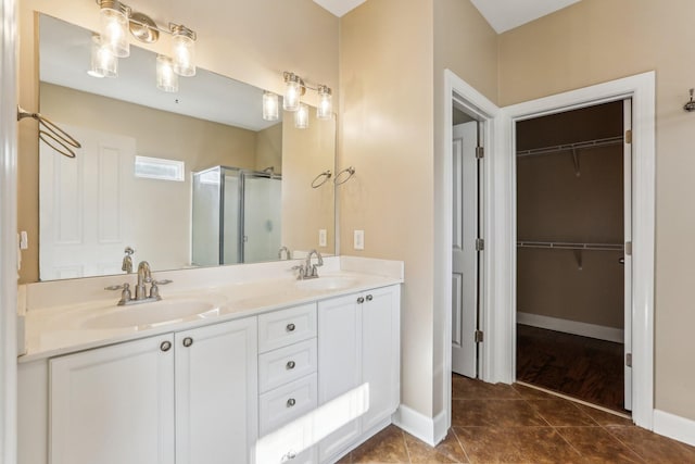 full bathroom featuring a spacious closet, double vanity, a stall shower, and a sink