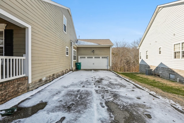 view of home's exterior featuring an attached garage, central AC unit, and concrete driveway