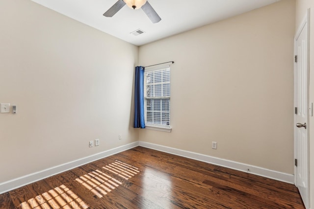 empty room featuring dark wood-style floors, a ceiling fan, visible vents, and baseboards