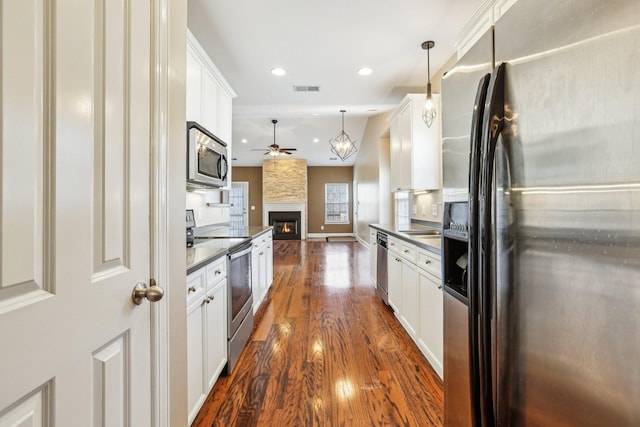 kitchen with dark wood-style flooring, dark countertops, visible vents, appliances with stainless steel finishes, and open floor plan