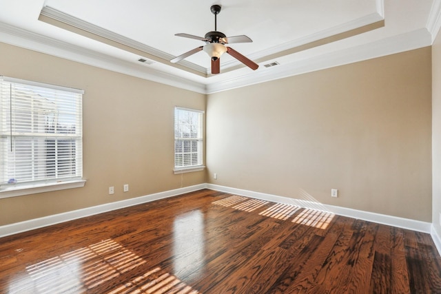 empty room featuring ornamental molding, a raised ceiling, visible vents, and wood finished floors