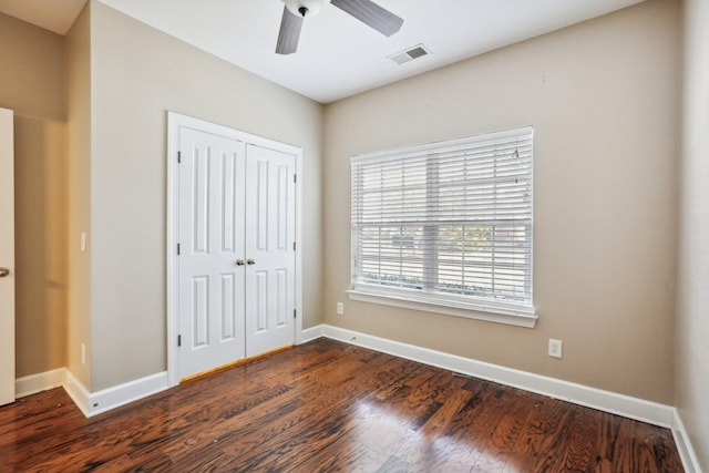 unfurnished bedroom with ceiling fan, wood finished floors, visible vents, baseboards, and a closet