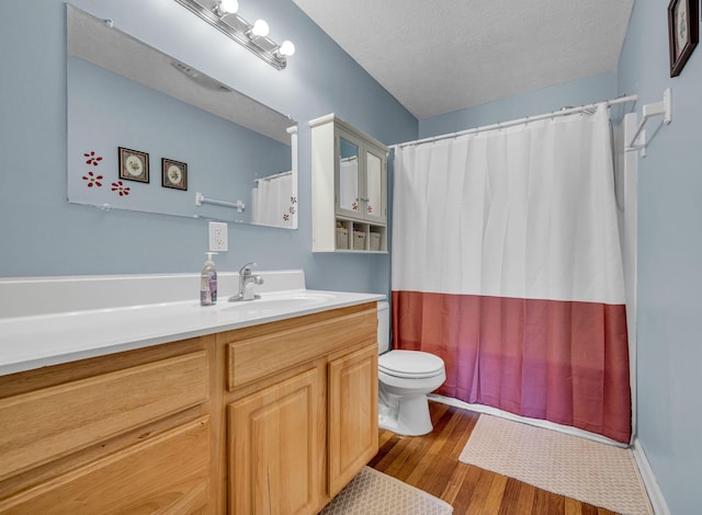 full bath with a textured ceiling, curtained shower, toilet, wood finished floors, and vanity