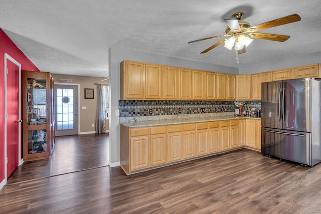 kitchen with dark wood-style floors, freestanding refrigerator, light brown cabinets, and backsplash