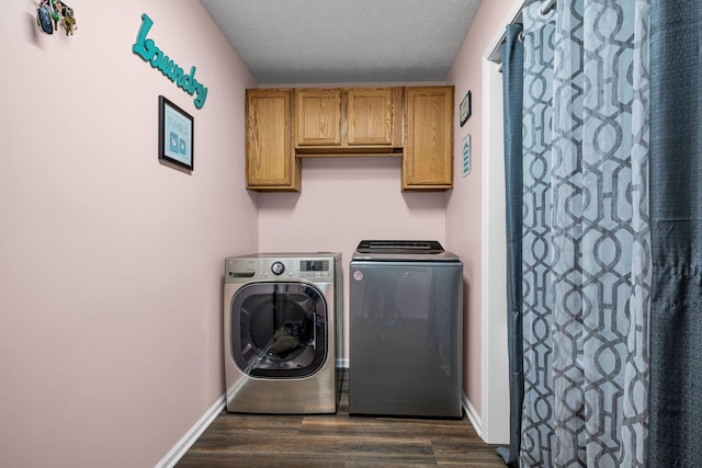 washroom featuring dark wood-style floors, washer and clothes dryer, cabinet space, and baseboards