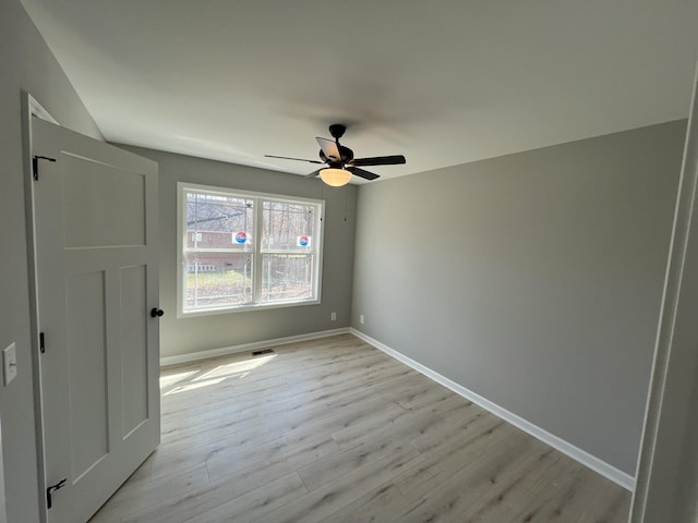 unfurnished room featuring light wood finished floors, visible vents, baseboards, and ceiling fan