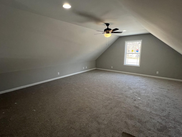 additional living space featuring vaulted ceiling, ceiling fan, dark carpet, and baseboards