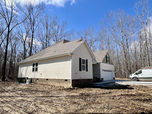 view of side of property with central air condition unit, a garage, a shingled roof, concrete driveway, and crawl space