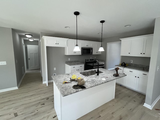 kitchen with light wood-type flooring, white cabinets, stainless steel microwave, and a sink