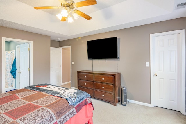 bedroom with visible vents, a ceiling fan, a tray ceiling, baseboards, and light colored carpet