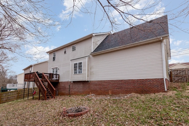 rear view of house featuring roof with shingles, a deck, stairs, and fence