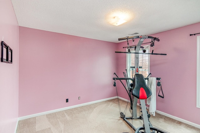 exercise area featuring carpet flooring, baseboards, visible vents, and a textured ceiling