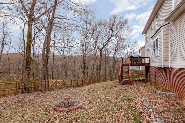 view of yard with a fenced backyard, a fire pit, stairs, and a deck