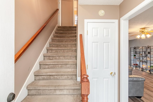 stairs featuring a textured ceiling, a ceiling fan, and wood finished floors