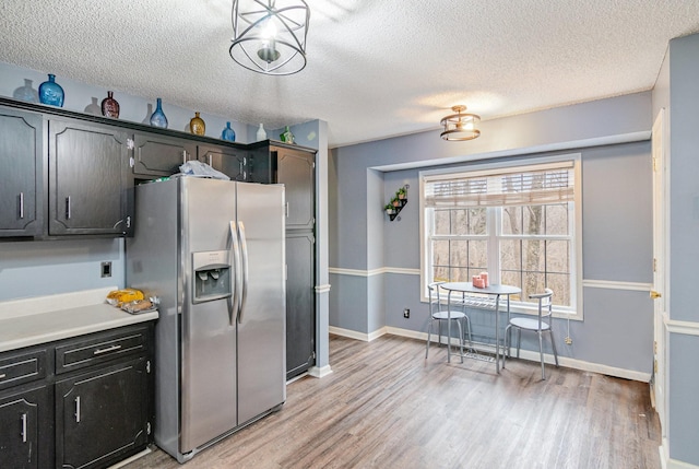 kitchen featuring baseboards, light wood-style flooring, light countertops, a textured ceiling, and stainless steel fridge